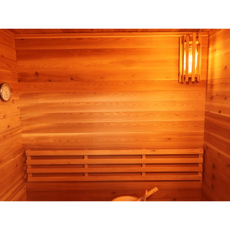 SunRay Seneca HL300DS Home Steam Sauna - interior back wall, showing the interior light illuminated top right , hygrometer on the left wall and the bucket on the bench (bottom of picture).