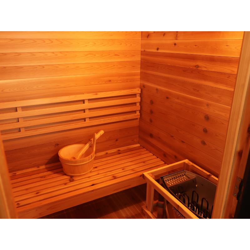 SunRay Seneca HL300DS Home Steam Sauna - interior view showing the bucket on the bench and the sauna heater to the right, without rocks.
