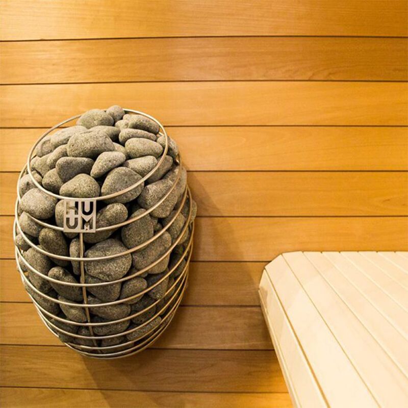 The HUUM Drop sauna heater mounted on the wall of a sauna
