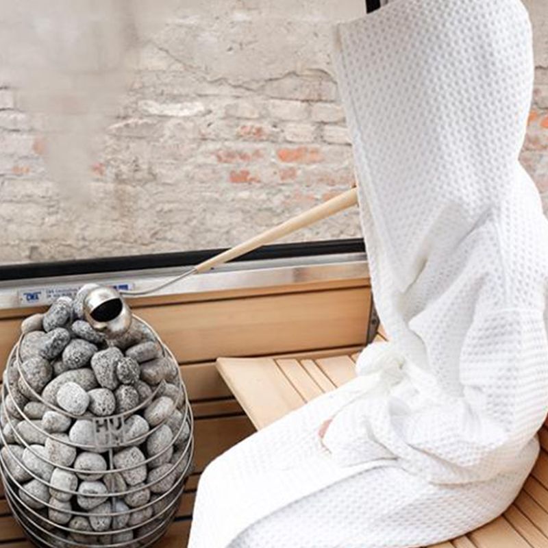 Person pouring water on HUUM DROP sauna heater
