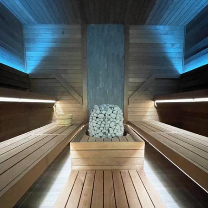 HIVE Series 18 kW Sauna Heater - in a sauna, center, with two benches on either side with back lighting