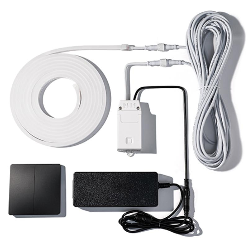 A wired control or sensor kit laid out on a white background, including a coiled white cable, a white junction/control box, a black rectangular sensor or switch, and a black power adapter.