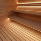 Wooden sauna interior with tiered wooden benches and a slatted floor, illuminated by warm built-in LED strip lighting.