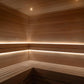 A wooden sauna interior with tiered seating, light wood plank walls and ceiling, and warm built-in LED lighting along the corners.