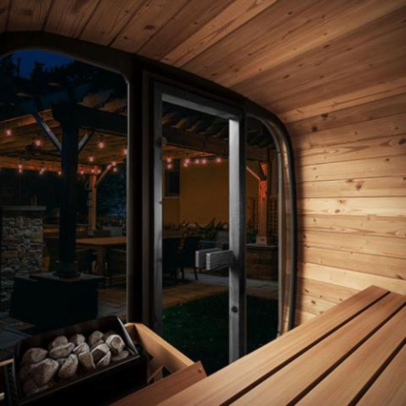 Sauna Life  CL4G Home Cube Sauna - interior looking out through the glass front. Night time on a patio with patio lights. Interior catches view of benches and heater on the left.