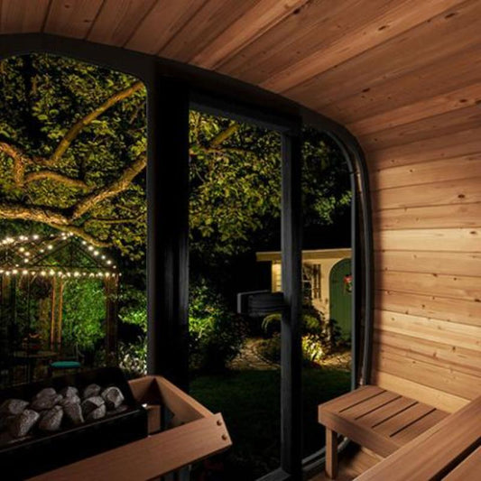 Sauna Life Model CL5G Home Cube Sauna - view from the interior looking out the glass front to a night time lit patio with trees and lights.