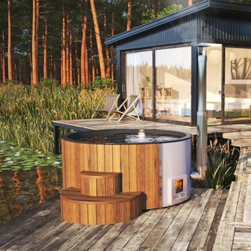 Wood-Fired Hot Tub S4N - in a woodland setting next to a pond and building, sitting on a wooden deck