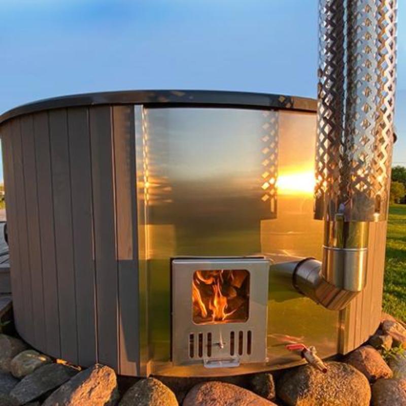 Wood-Fired Hot Tub S4N - close up view of wood stove on the side of the hot tub, sitting on stones, blue sky background