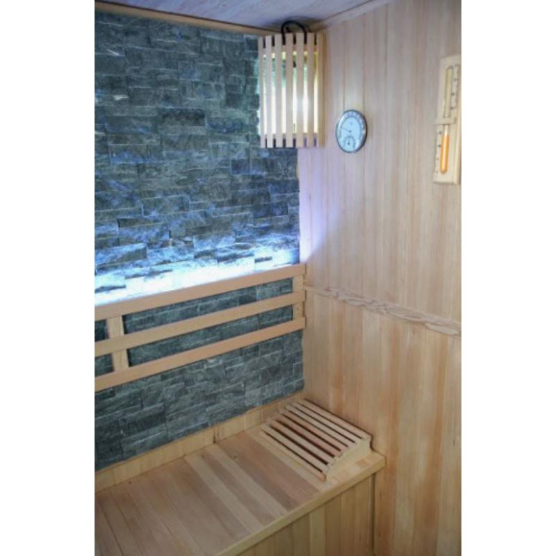 Westlake 3 Person Traditional Sauna - view of rock sauna wall and bench backrest with back lighting. Top right corner is a sauna light with hygrometer on the wall beside it.