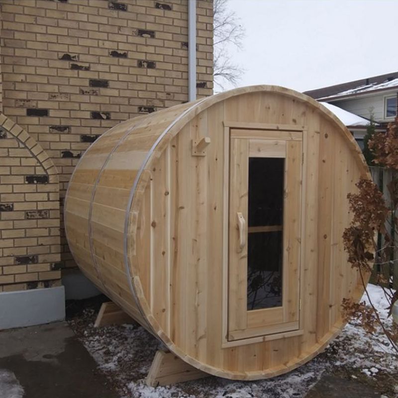 Dundalk Harmony 4 Person Barrel Sauna - placed in a backyard beside a brick building